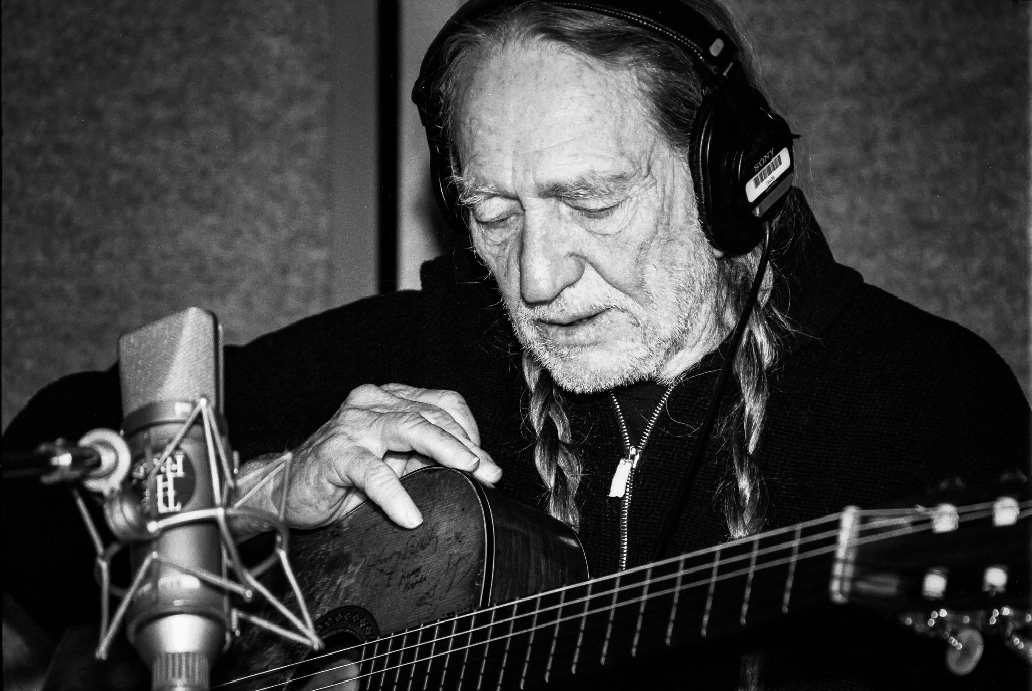 Willie Nelson holding guitar in recording booth